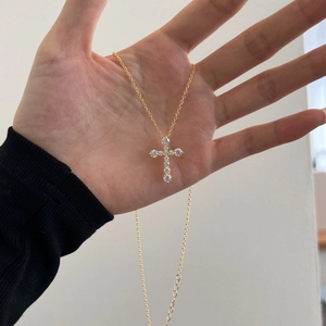 Detailansicht einer goldenen Kreuzkette mit funkelnden Zirkonia-Steinen für Damen