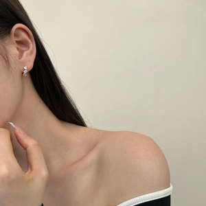 Side view of an Asian model wearing minimalist silver stud earrings with zircon stones