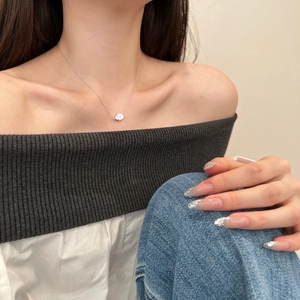 Detail of silver S925 Hamsa Hand pendant necklace on a female model neck