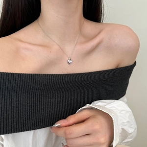 Detail of S925 silver heart necklace with a small zircon on a female neck line