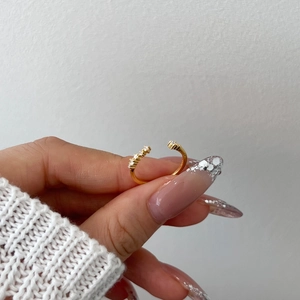 Dettaglio di un anello regolabile in oro con croce e piccoli zirconi bianchi sulla mano
