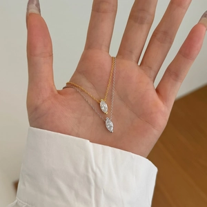 Detail von Silber- und Goldketten mit Marquise-Zirkonia-Anhängern, von Hand gehalten