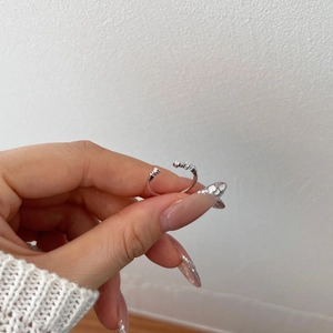 Dettaglio anello a croce in argento S925 con pietre di zircone tenuto nella mano