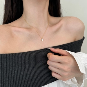 Détail d'un collier en argent doré avec pendentif en zircon ovale porté sur la clavicule