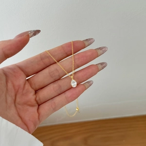 Gros plan sur un collier en or avec pierre de zircon ovale et serti à griffes classique