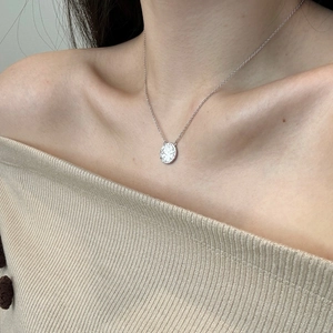 Close-up of S925 sterling silver necklace with textured oval disc pendant on neck