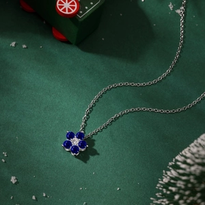 Détail du pendentif fleur de prunier de Noël avec gemmes bleues sur fond hivernal