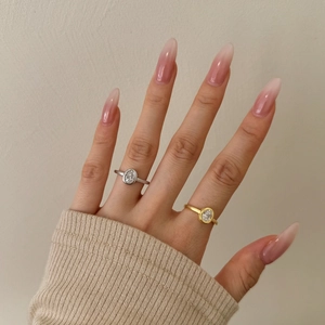 Detail of oval-cut zircon rings in silver and gold plating on a model's hand