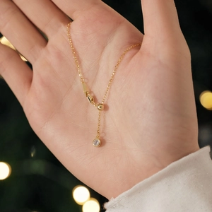 Macro shot of an adjustable gold necklace featuring a round sparkling zircon pendant