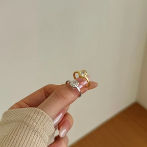 Detail of matte gold and silver rings with round zircon settings on fingers