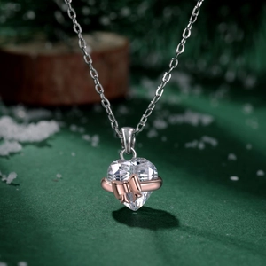 Macro-opname van hartvormige kristallen ketting met roségouden strik op zilver