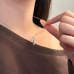 Close-up of S925 sterling silver cross pendant necklace with zircon on brown sweater