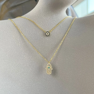 Detail of layered S925 silver necklaces with Hamsa hand and evil eye zircon pendants