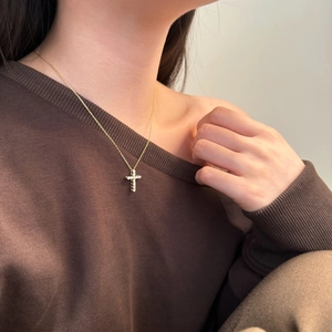 Elegant gold S925 sterling silver cross necklace with pavé zircons worn by a model