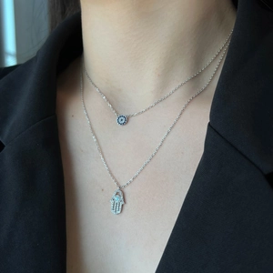 Close-up of S925 sterling silver Hamsa hand and Evil Eye layered necklaces with zircons