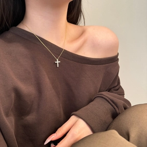 Close-up of golden S925 silver cross necklace with zircons on a female model