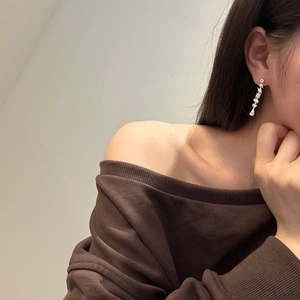 Close-up of sparkling silver tassel earrings with zircon stones worn by a model