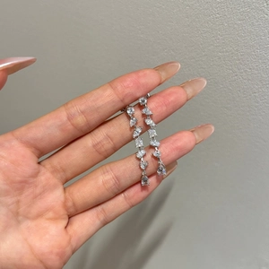 Macro detail of S925 silver tassel earrings featuring multi-cut zircon stones in a hand