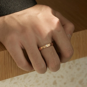 Détail macro de bague en or rose avec zircon portée sur la main sur fond minimaliste