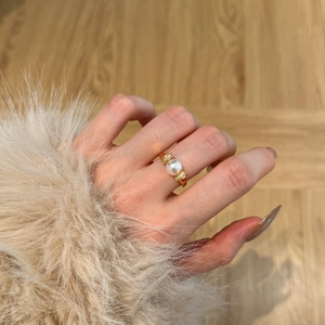 Close-up of 8mm pearl ring with gold plating and sparkling side stones on a finger