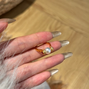 Elegant gold ring with 8mm pearl and ruby accents worn on a hand in a close-up shot