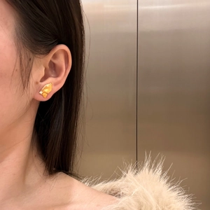 Detailed view of a gold butterfly earring with matte texture and sparkling accents