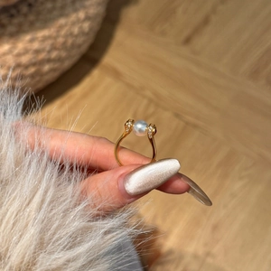 Close-up of elegant 8mm pearl ring with pavé stones on gold-plated band held by model
