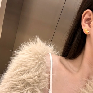 Detailed close-up of yellow butterfly stud earring with zircon on model's ear