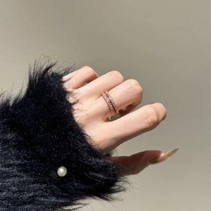 Detailed view of gold plated eternity ring with pink and white zirconia on a hand