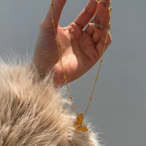 Macro view of gold butterfly pendant with sparkling zircons on a beaded chain