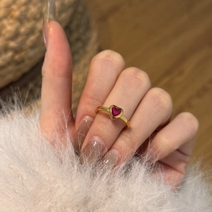 Detailed view of a gold-plated heart ring with a vibrant red heart-shaped gemstone