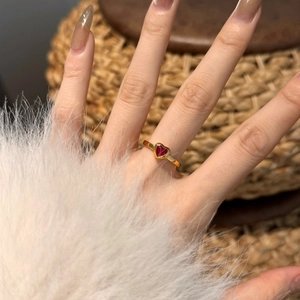 Macro detail of S925 silver heart ring with red zircon inlay on model hand