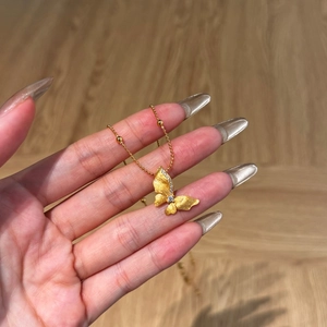Close-up of matte gold butterfly pendant necklace with crystal accents and bead chain