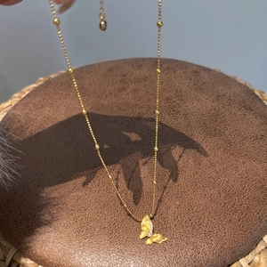 Detail of a 22K gold plated silver butterfly necklace with brushed texture and crystals