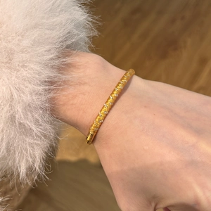Detailed view of golden woven texture bangle with sparkling zircon inlay and side clasp