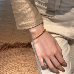 Close-up of gold snake texture bangle with purple zircon inlay on model's wrist