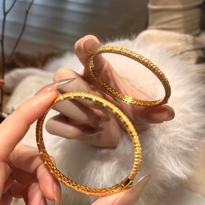 Detail of two golden snake skin textured bangles with zircon inlay on white fur