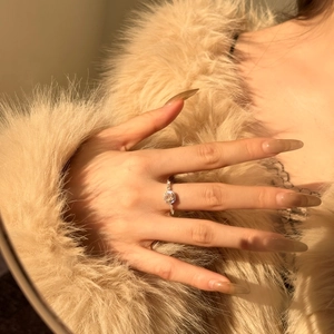 Close-up of a S925 sterling silver ring with halo pink stone on a luxury fur background