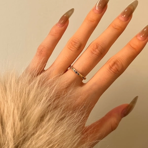 Dettaglio di anello sottile dorato con zirconi blu sulla mano con polsino in pelliccia