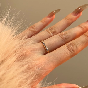 Dettaglio di un anello dorato vintage con pietre blu indossato da una modella