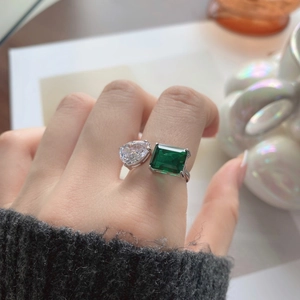 Gros plan d'une bague en argent S925 avec pierres émeraude et goutte sur le doigt