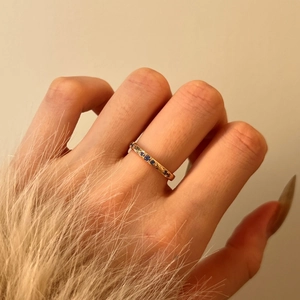 Dettaglio dell'anello vintage dorato con zirconi blu e incisione floreale sulla mano