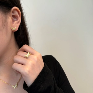 Detailopname van gouden vlinder sieradenset met ketting, ring en oorbellen op model