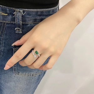 Macro shot of silver spiral open ring featuring emerald cut green stone and clear zircon
