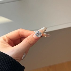 Detail of a sparkling round-cut solitaire zircon ring held in hand with a classic silver band