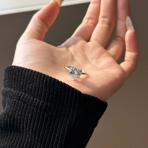 Macro view of a polished heart-shaped gemstone ring with silver band in hand