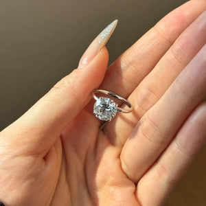 Detailed macro view of a round brilliant-cut solitaire diamond set in a four-prong silver ring