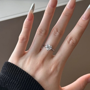 Close-up of heart-cut sparkling gemstone ring on a hand with minimalist silver band