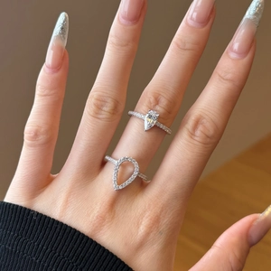 Detail of stacked S925 sterling silver rings with pear-shaped hollow design on finger