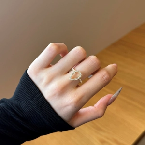 Detailed view of a gold-plated teardrop ring with pavé diamonds on a model's finger